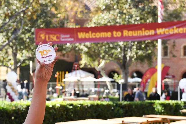 hand holding a 10th reunion sticker in from of a Welcome to Reunion banner