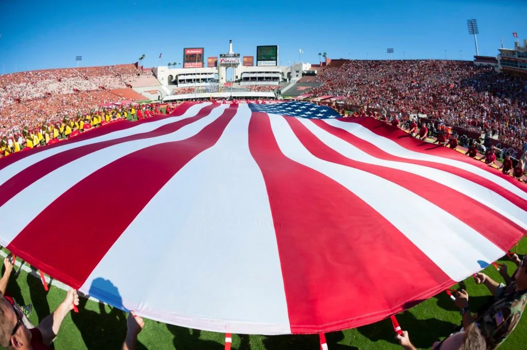 unfurling of a flag of the United Stated of America inside the Los Angeles Coliseum