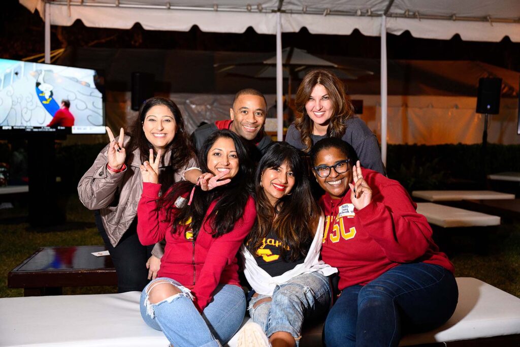 a group of USC alumni lean close together for a group photo