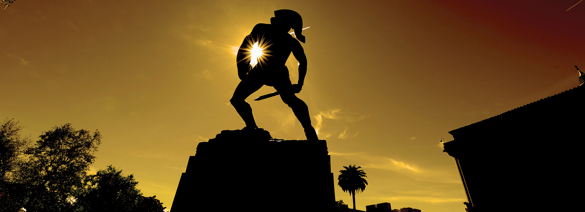 Tommy Trojan silhouetted against a yellow sunset