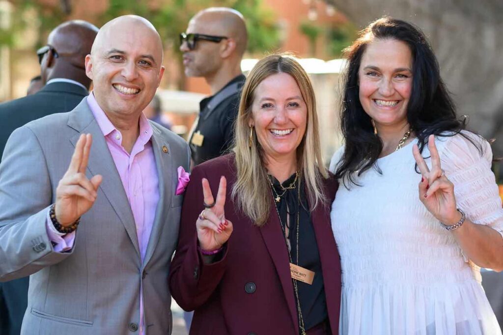 alumni leaders pose with a 'fight on' gesture