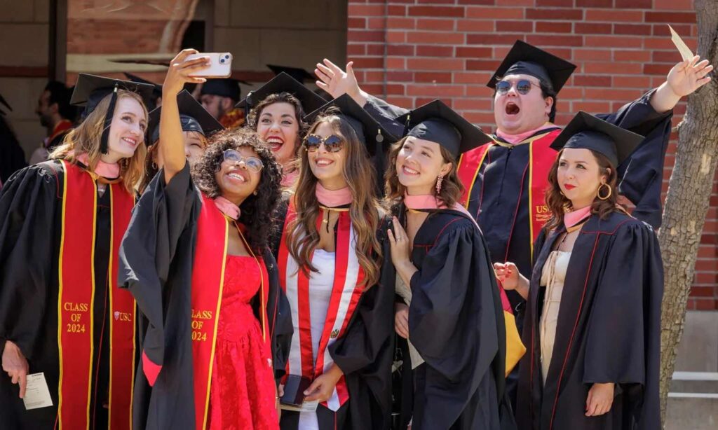 new graduates take a group selfie at 2024 Commencement