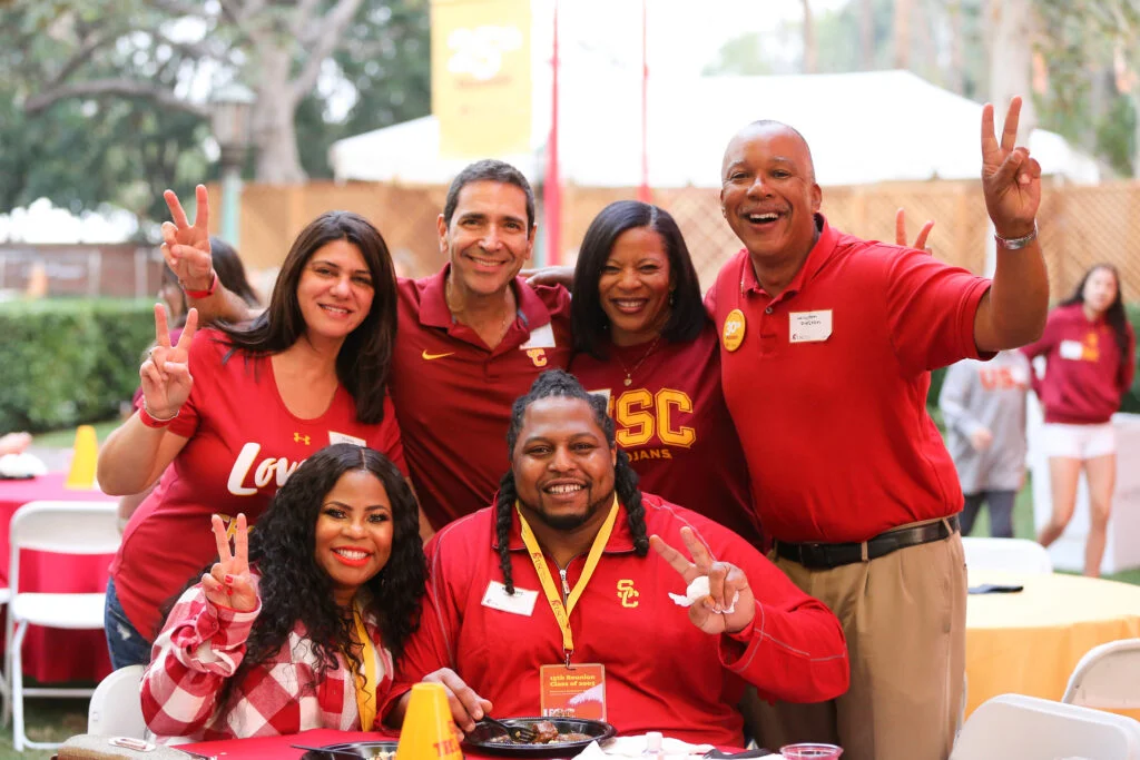 six people gather at a table for a photo wearing USC shirts