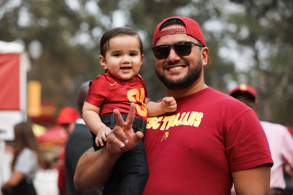 a man holds his young son at an alumni event