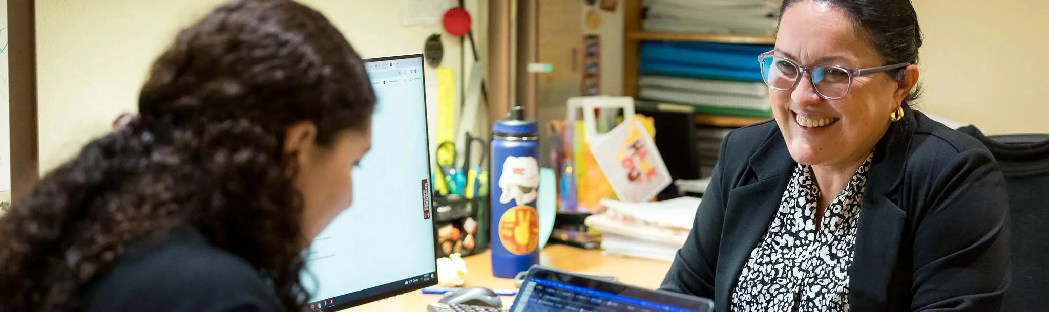 two women have a conversation in an office