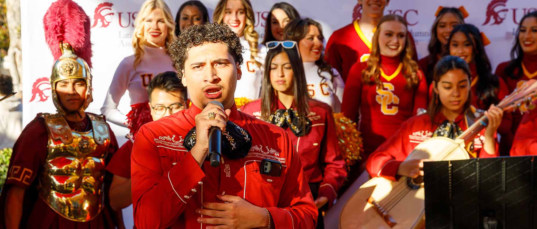 man sings with a band behind him at a Litano Alumni Association tailgate