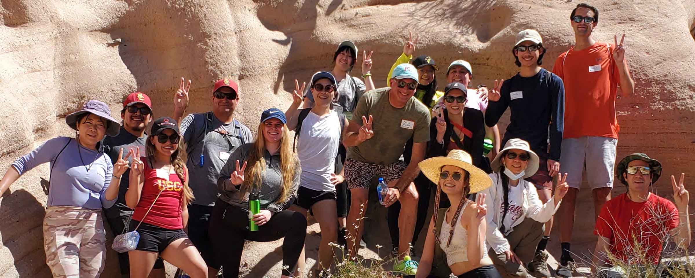 group of alumni posing beside a sedimentary rock formation on a hike