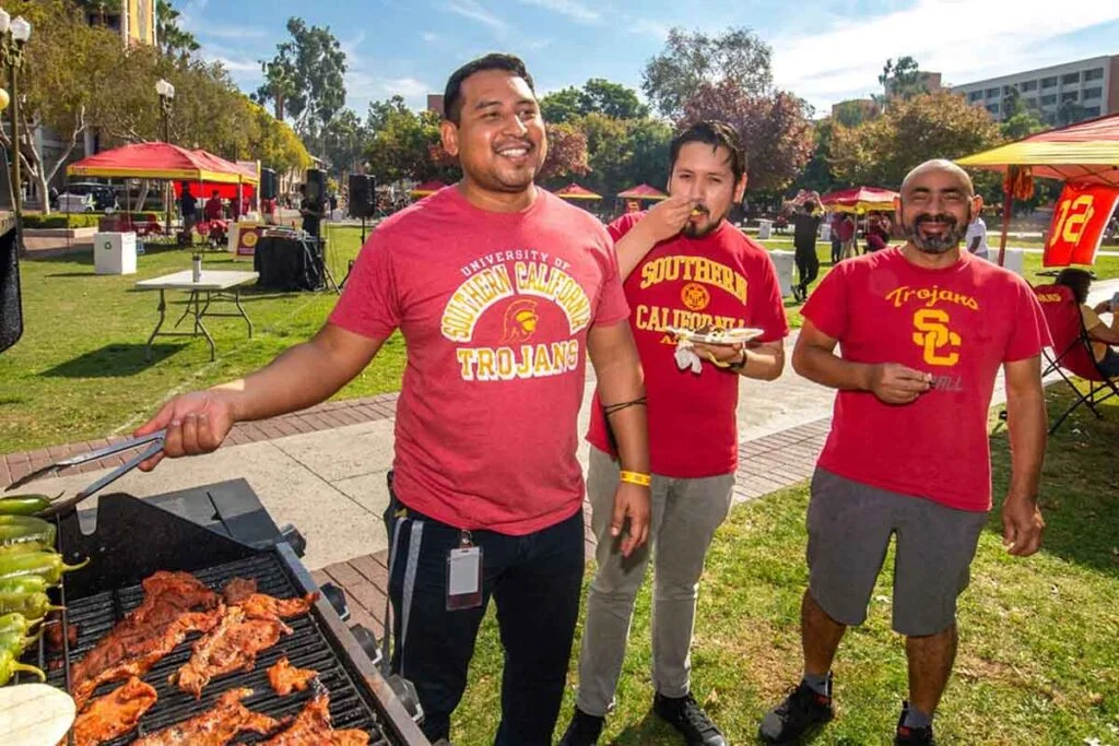 three men in USC shirts grilling on campus