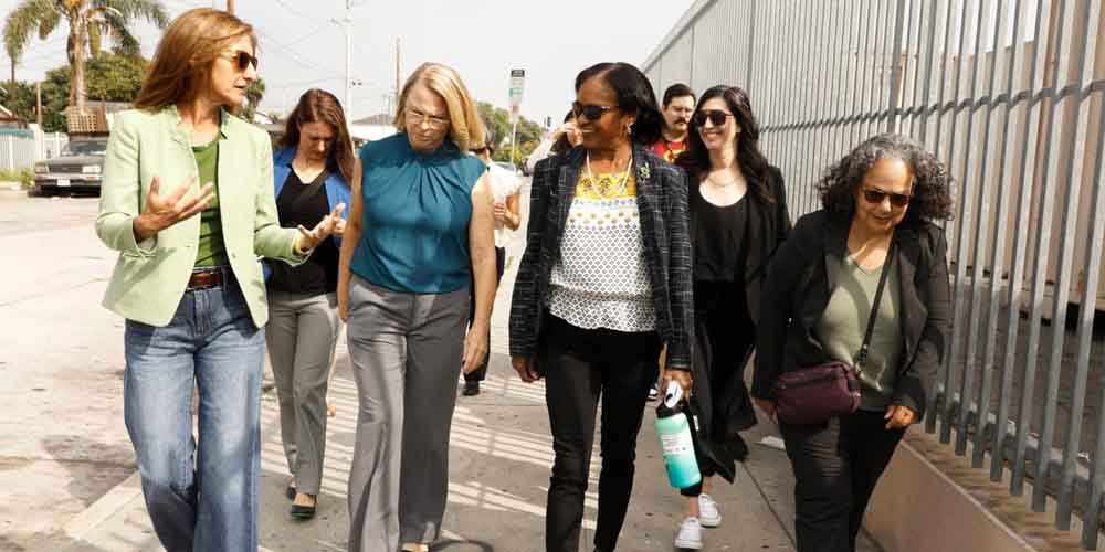 women converse while walking down the sidewalk